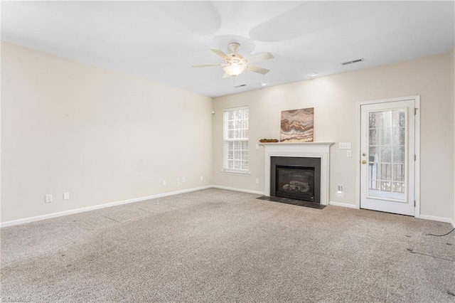 unfurnished living room featuring visible vents, a fireplace with flush hearth, carpet floors, baseboards, and ceiling fan