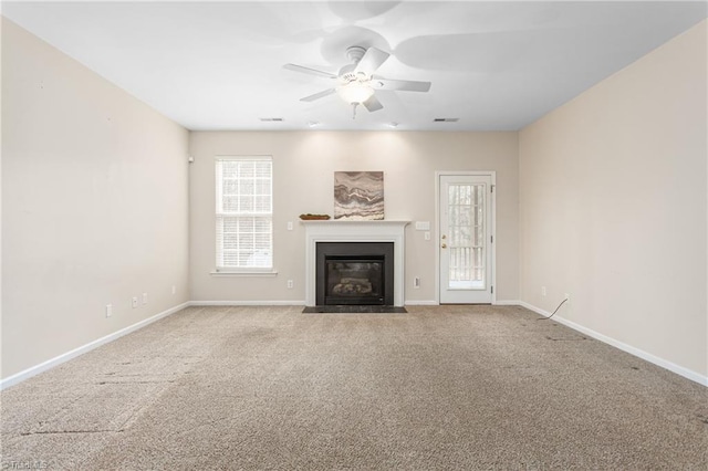 unfurnished living room featuring a fireplace with flush hearth, carpet, baseboards, and ceiling fan