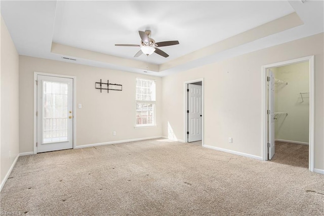 unfurnished room featuring visible vents, baseboards, a tray ceiling, carpet floors, and a ceiling fan