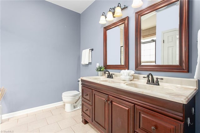 bathroom with double vanity, toilet, baseboards, and a sink