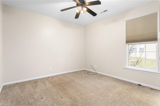 carpeted empty room with visible vents, a ceiling fan, and baseboards