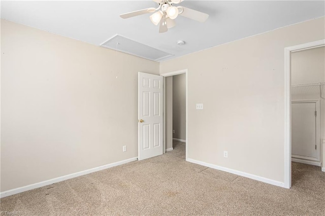 unfurnished bedroom with baseboards, carpet, attic access, and a spacious closet