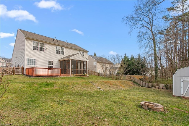 rear view of house with a fenced backyard, a sunroom, an outdoor structure, a fire pit, and a storage shed