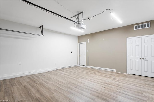 garage featuring visible vents, baseboards, and a garage door opener