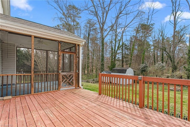 deck with a yard, an outbuilding, a storage shed, and a sunroom