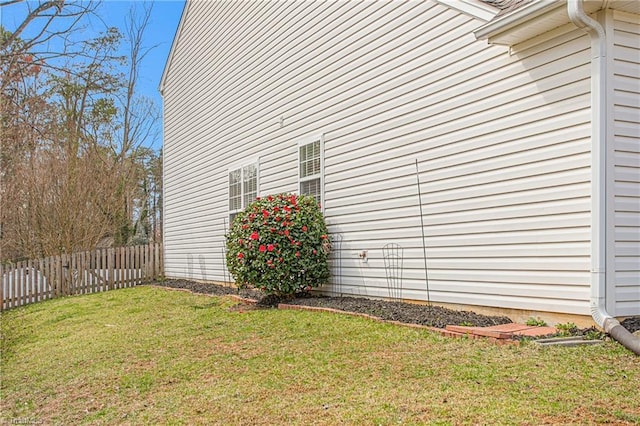 view of side of home with a yard and fence