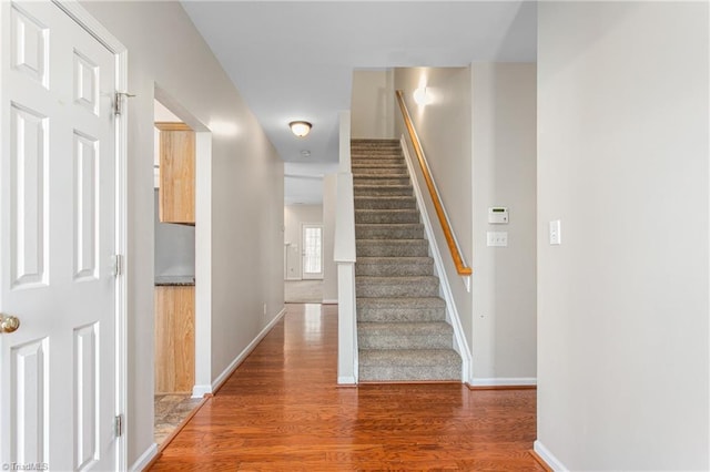 staircase with baseboards and wood finished floors