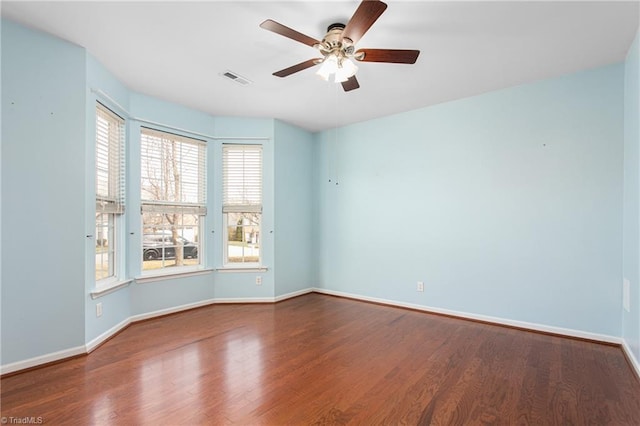 empty room with visible vents, baseboards, wood finished floors, and a ceiling fan