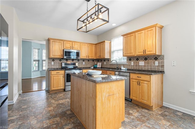 kitchen featuring stone finish flooring, baseboards, appliances with stainless steel finishes, and a center island