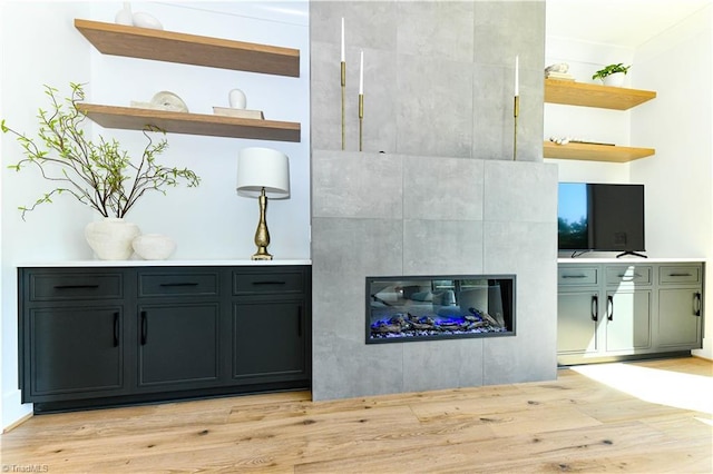 bar featuring a tiled fireplace and light wood-type flooring