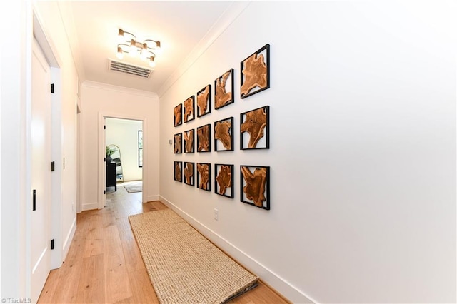 hall with visible vents, ornamental molding, light wood finished floors, and baseboards