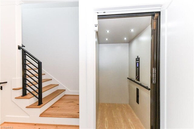 stairs featuring recessed lighting, elevator, and wood finished floors