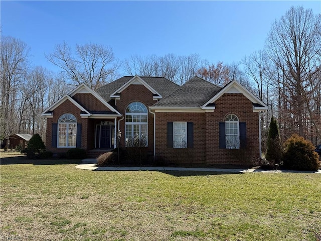 view of front of property featuring brick siding, a front lawn, and a shingled roof