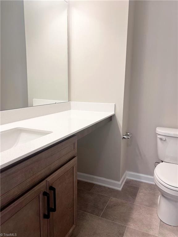 bathroom featuring toilet, vanity, and tile patterned flooring