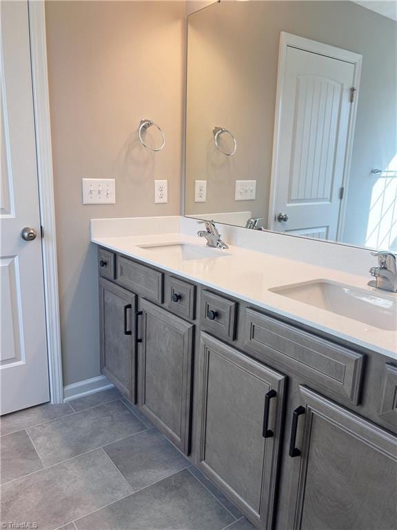 full bathroom with a sink, double vanity, and tile patterned floors