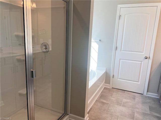 full bathroom with a bath, a stall shower, and baseboards