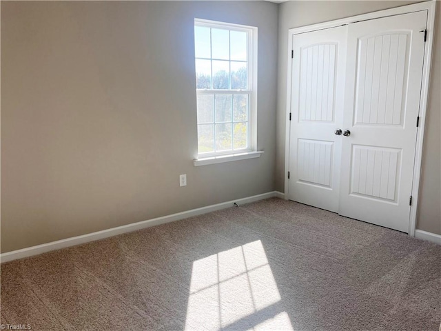 unfurnished bedroom with carpet, a closet, and baseboards