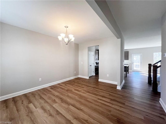 unfurnished room featuring a notable chandelier and dark hardwood / wood-style floors