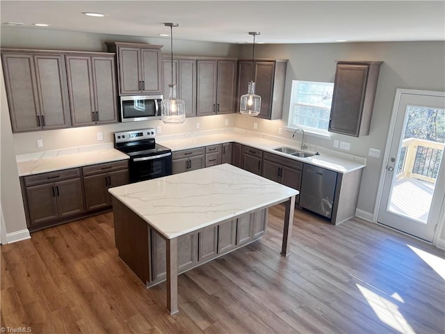 kitchen with a sink, stainless steel appliances, a kitchen island, and dark wood-style floors