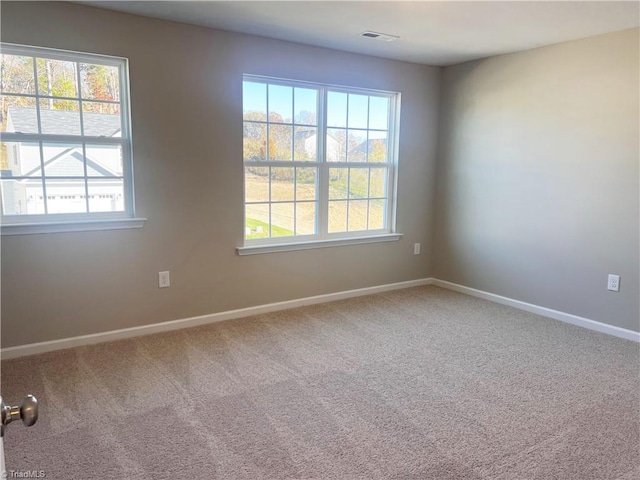 carpeted spare room with visible vents and baseboards