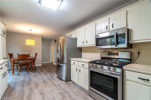 kitchen with decorative light fixtures, stainless steel appliances, light hardwood / wood-style flooring, and white cabinetry