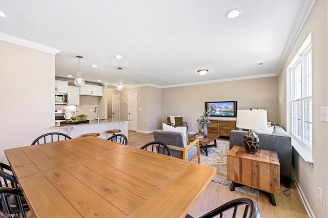 dining room with crown molding, baseboards, recessed lighting, and light wood-style flooring