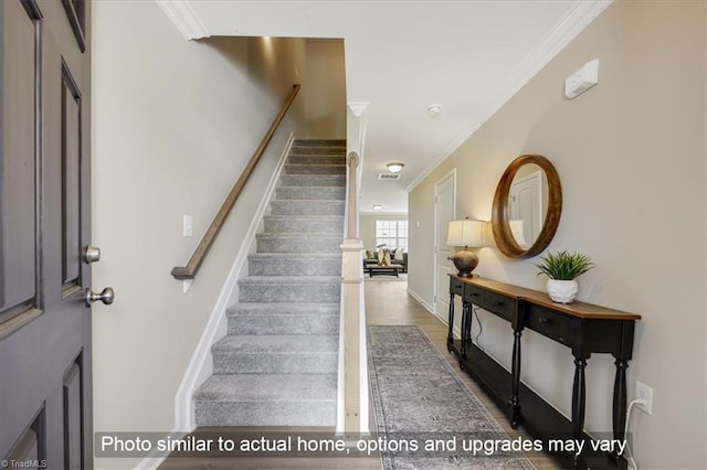 staircase featuring crown molding, baseboards, visible vents, and wood finished floors