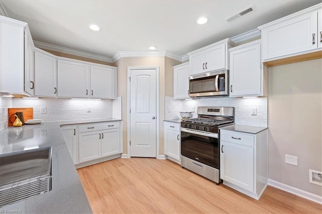 kitchen with visible vents, light wood-style floors, white cabinetry, appliances with stainless steel finishes, and backsplash
