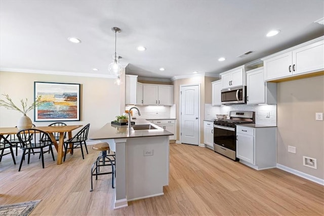 kitchen featuring visible vents, ornamental molding, light wood-type flooring, a sink, and appliances with stainless steel finishes