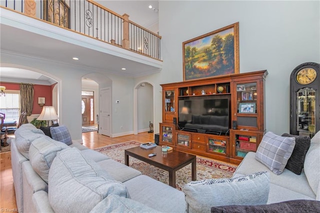 living room featuring a high ceiling, light hardwood / wood-style floors, and crown molding