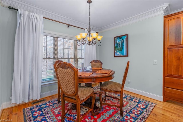 dining area featuring light hardwood / wood-style floors, ornamental molding, and a notable chandelier