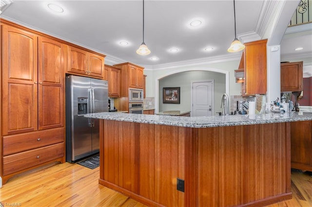 kitchen with light stone counters, kitchen peninsula, light hardwood / wood-style floors, decorative light fixtures, and appliances with stainless steel finishes