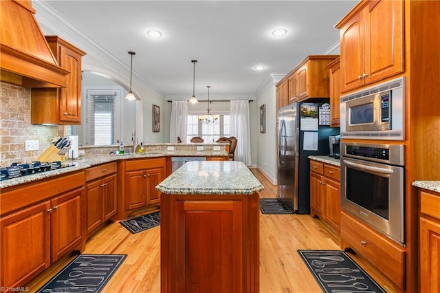 kitchen with sink, a center island, light wood-type flooring, and appliances with stainless steel finishes