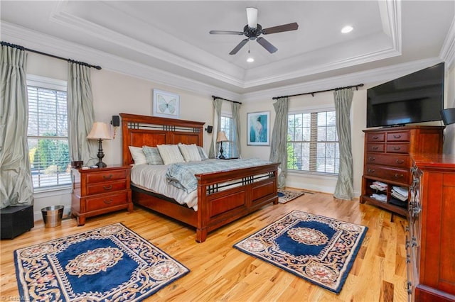 bedroom featuring hardwood / wood-style flooring, a raised ceiling, multiple windows, and ceiling fan