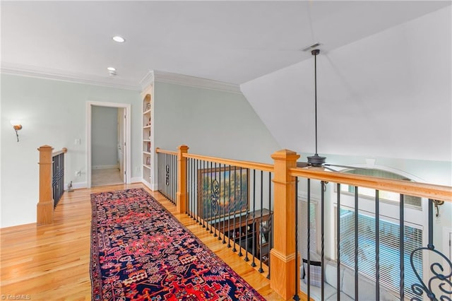 hallway with built in shelves, crown molding, vaulted ceiling, and hardwood / wood-style flooring