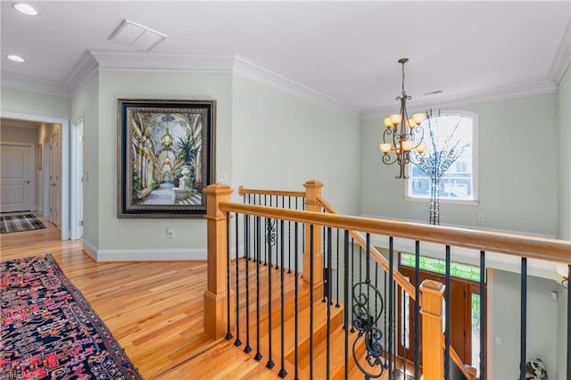 hall featuring ornamental molding, hardwood / wood-style flooring, and a notable chandelier