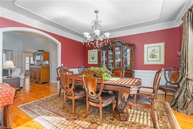 dining room with crown molding, light hardwood / wood-style floors, and an inviting chandelier