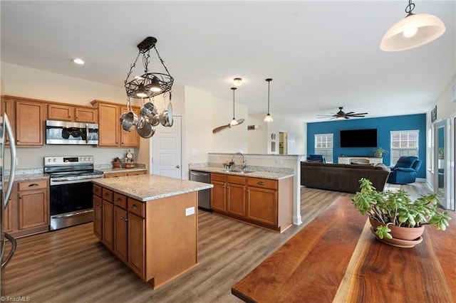 kitchen featuring sink, a center island, hanging light fixtures, appliances with stainless steel finishes, and hardwood / wood-style flooring