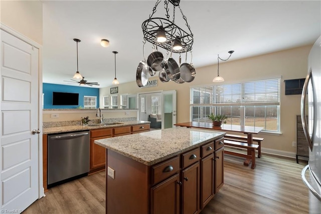 kitchen with appliances with stainless steel finishes, sink, pendant lighting, and light stone counters