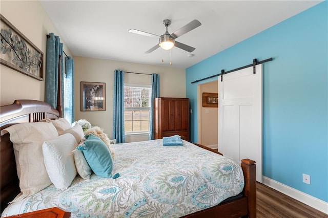 bedroom with dark wood-type flooring, ceiling fan, and a barn door