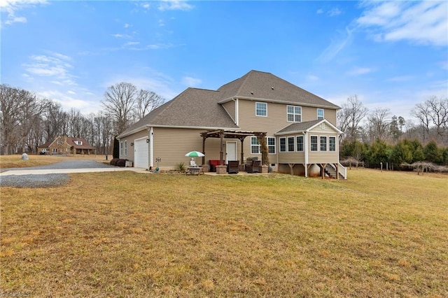 back of property featuring a garage, a pergola, a lawn, and a sunroom