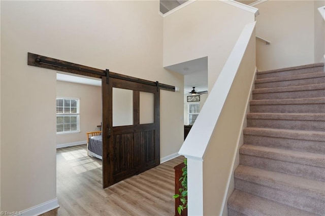 stairs featuring hardwood / wood-style flooring, a barn door, a high ceiling, and ceiling fan