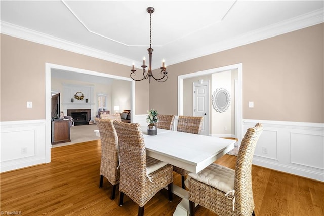 153 Montauk Ct, Clemmons, NC 27012 - dining space with a chandelier, a wainscoted wall, wood finished floors, crown molding, and a fireplace
