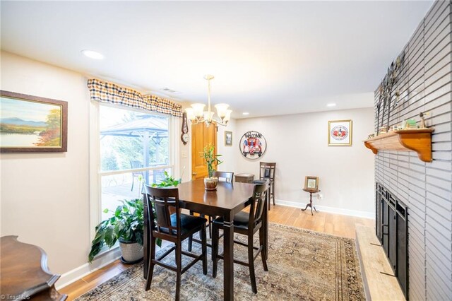 144 Collins Rd, Sparta, NC 28675 - dining room with a fireplace, light wood-type flooring, and a notable chandelier