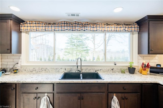 144 Collins Rd, Sparta, NC 28675 - kitchen featuring backsplash, light stone counters, dark brown cabinetry, and sink