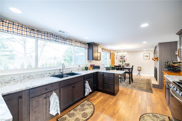 144 Collins Rd, Sparta, NC 28675 - kitchen with sink, decorative light fixtures, a fireplace, stainless steel stove, and light wood-type flooring