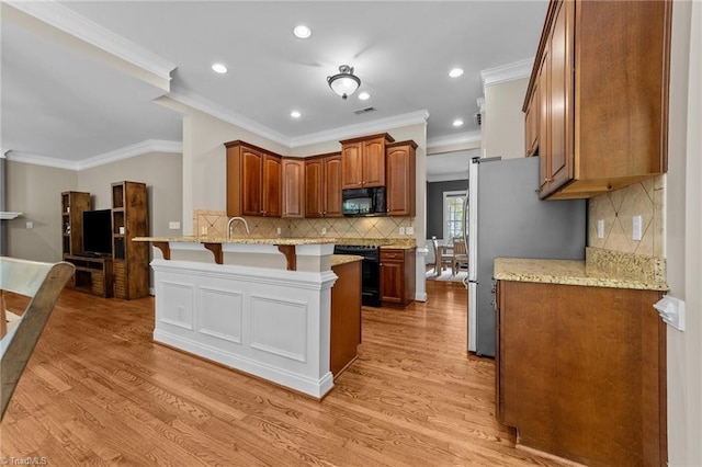 kitchen with a peninsula, light wood-style floors, a breakfast bar area, recessed lighting, and black appliances