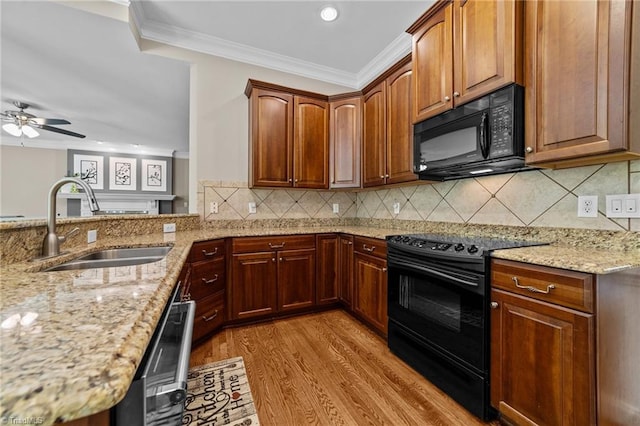 kitchen with a sink, ornamental molding, light stone countertops, and black appliances