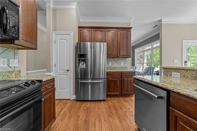 kitchen with crown molding, backsplash, black appliances, and light wood-type flooring