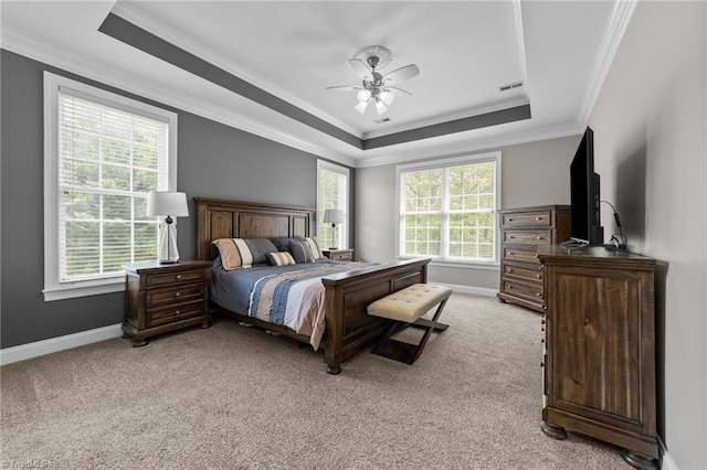 bedroom with light colored carpet, ornamental molding, a tray ceiling, and multiple windows
